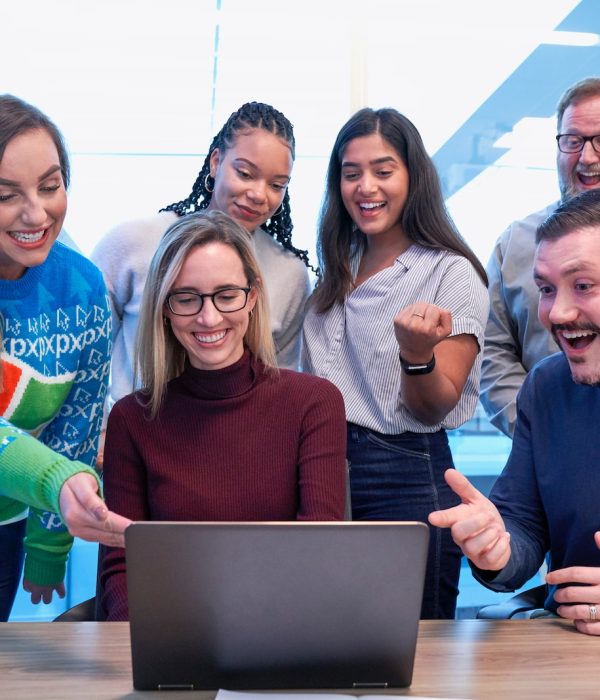 men and women sitting and standing while staring at laptop